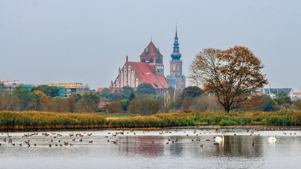 Blick über den Fluss auf die Stadt Greifswald mit den beiden Kirchtürmen